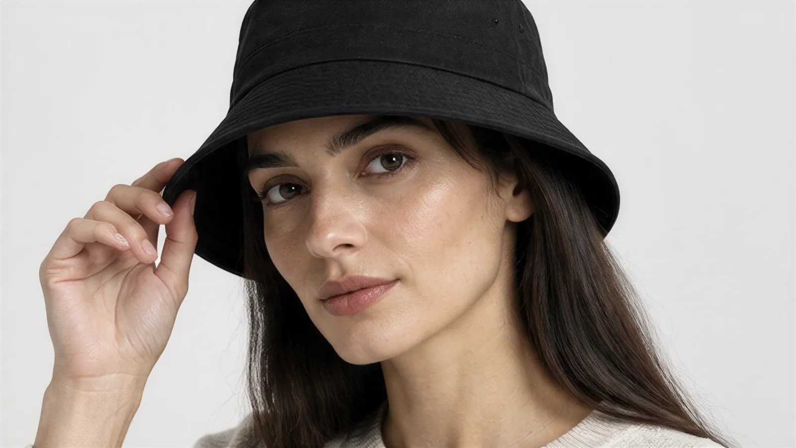 Black bucket hat worn with the model reaching up to the brim