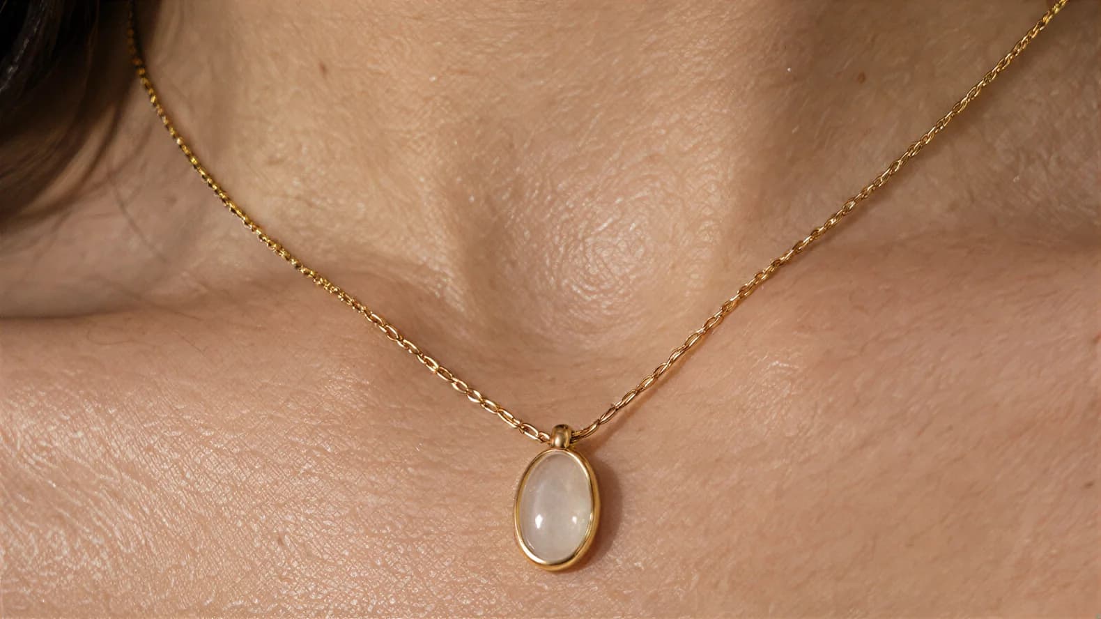 Close-up of the oval pendant resting below the collarbone