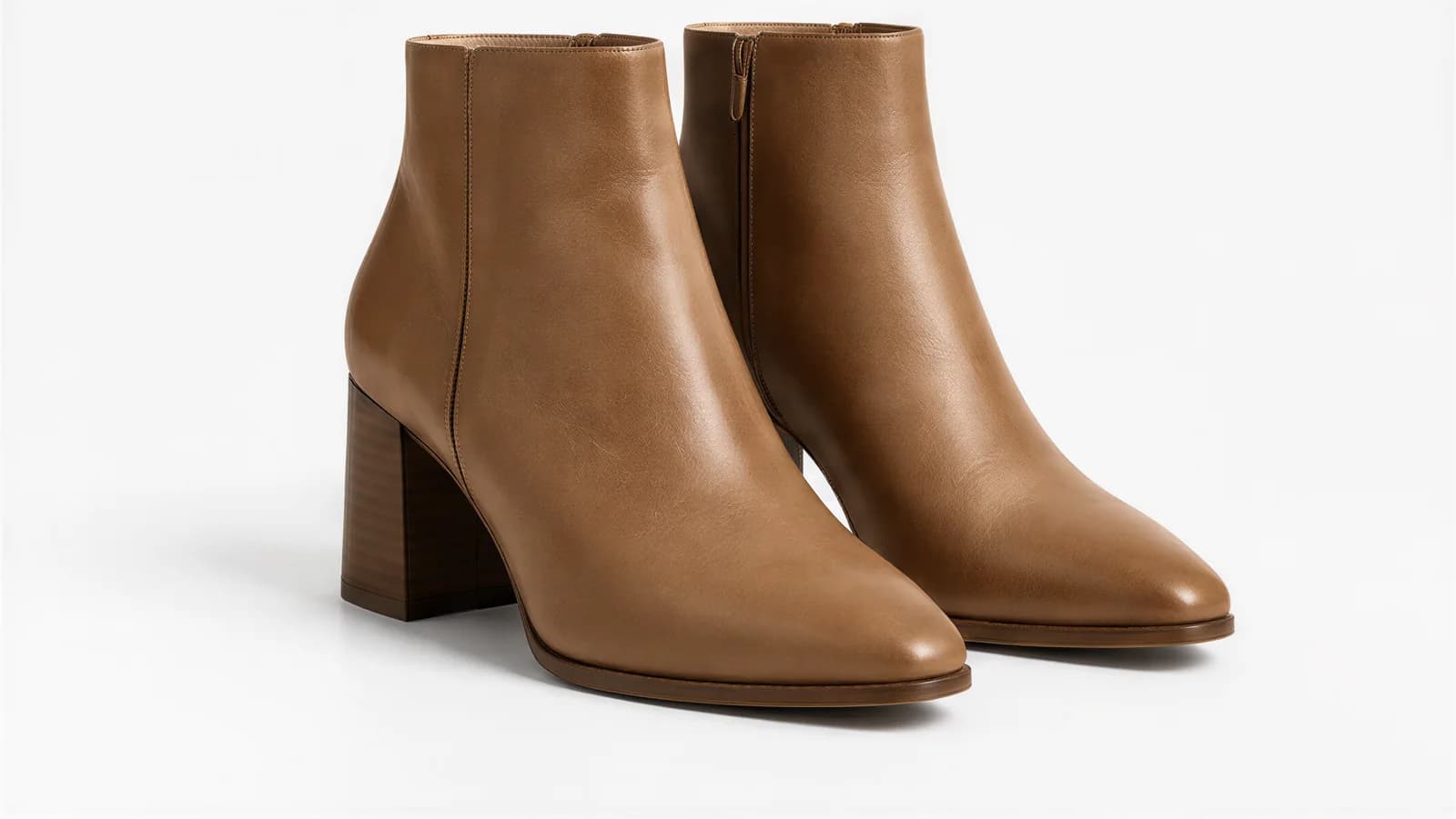A pair of tan leather ankle boots with stacked block heels on a white background