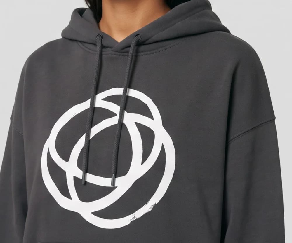A close-up of the white looped-circle print and drawcords on the charcoal hoodie, on the model, made with Tryly