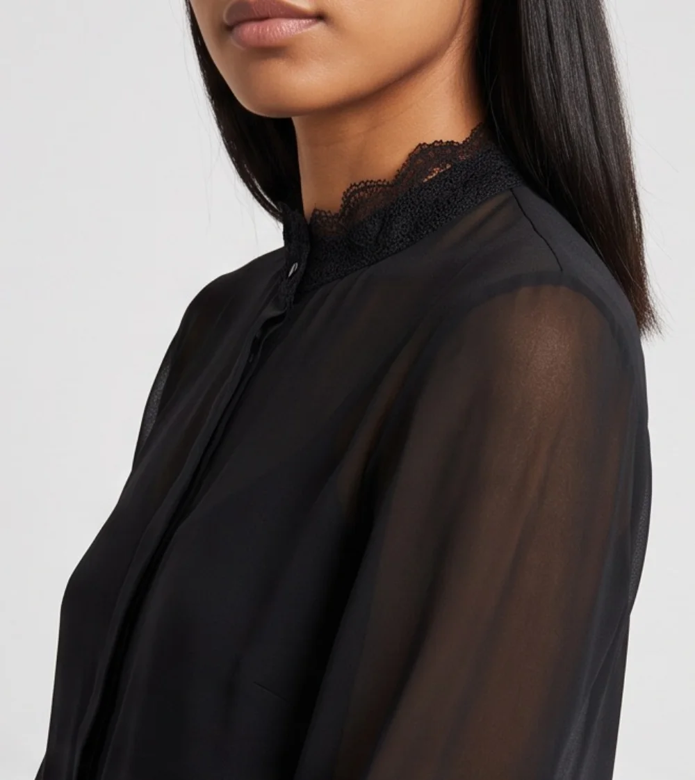 A close-up of the sheer black blouse on the model, showing the lace collar and the camisole under the chiffon sleeve