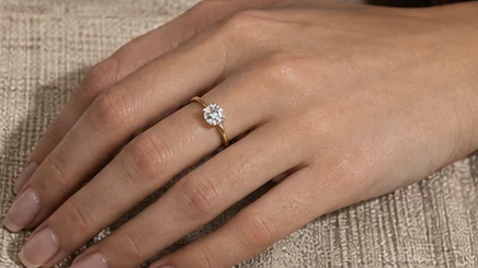Solitaire ring on a hand resting on linen